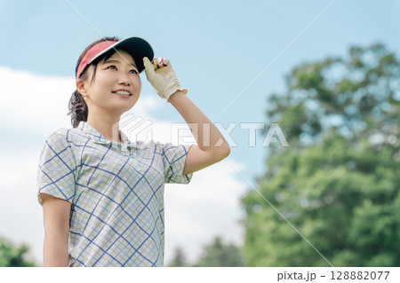 ゴルフ場でゴルフをするゴルファーの女性(笑顔) 128882077