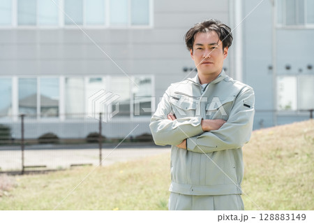 会社の前に立つ作業着姿の中年男性作業員 128883149