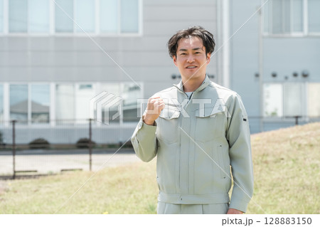 会社の前に立つ作業着姿の中年男性作業員 128883150