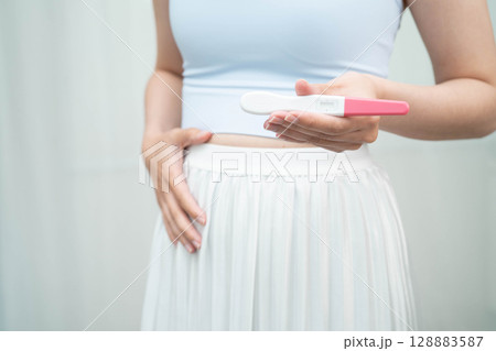 Asian holding pregnancy test for female of ovulation day, fetus, maternity, childbirth, birth control. Asian holding pregnancy test for female of ovulation day, fetus, maternity, childbirth, birth control. 128883587