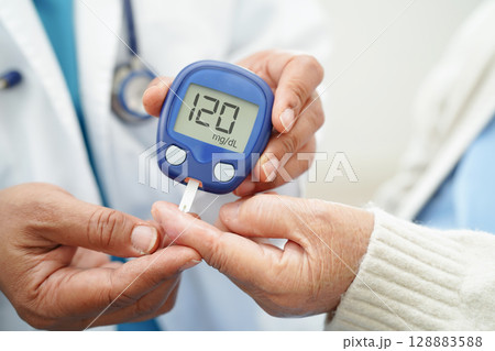 Asian doctor using digital glucose meter for check sample blood sugar level to treatment diabetes. 128883588