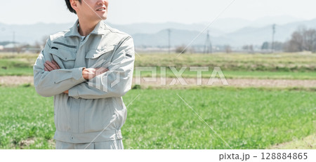 田舎の田んぼに立つ作業着姿のミドル世代の農家の男性 128884865