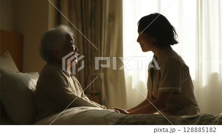 ベッドに横たわる高齢者に寄り添う医療従事者 ベッドに横たわる高齢者に寄り添う医療従事者 128885182