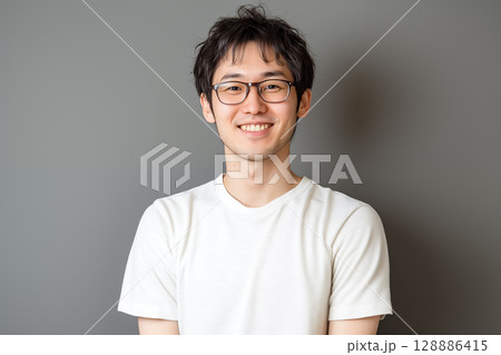 白いTシャツを着た若い日本人男性がグレーの背景の前で笑顔を見せるポートレート 128886415