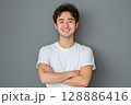 白いTシャツを着た若い日本人男性がグレーの背景の前で笑顔を見せるポートレート 128886416