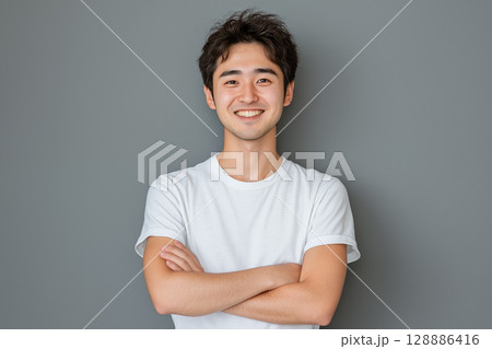 白いTシャツを着た若い日本人男性がグレーの背景の前で笑顔を見せるポートレート 128886416