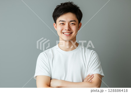 白いTシャツを着た若い日本人男性がグレーの背景の前で笑顔を見せるポートレート 128886418