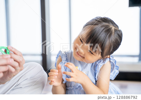おもちゃで遊ぶパパと娘の笑顔あふれる時間 128886792