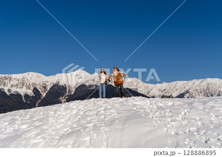 Couple Hiking Snow Mountains Winter: Joyful adventure in snowy mountain range during winter season. 128886895