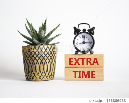 Extra time symbol. Concept word Extra time on wooden blocks. Beautiful white background with alarm clock and succulent plant. Business and Extra time concept. Copy space Extra time symbol. Concept word Extra time on wooden blocks. Beautiful white background with alarm clock and succulent plant. Business and Extra time concept. Copy space 128886988