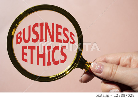 Business ethics symbol. Concept word Business ethics on magnifying glass. Businessman hand. Beautiful pink background. Business and Business ethics concept. Copy space 128887029