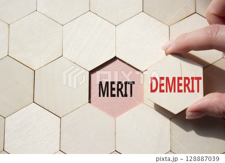 Merit or Demerit symbol. Concept word Merit or Demerit on wooden comb puzzle. Businessman hand. Beautiful pink background. Business and Merit or Demerit concept. Copy space 128887039