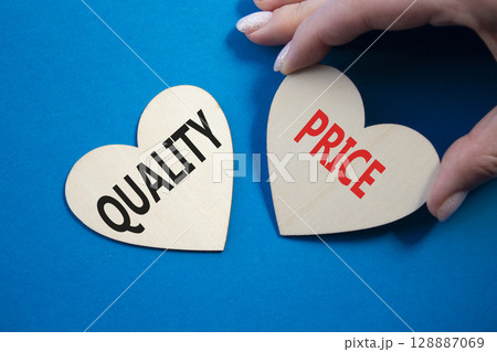 Price or Quality symbol. Concept word Price or Quality on wooden hearts. Businessman hand. Beautiful blue background. Business and Price or Quality concept. Copy space Price or Quality symbol. Concept word Price or Quality on wooden hearts. Businessman hand. Beautiful blue background. Business and Price or Quality concept. Copy space 128887069