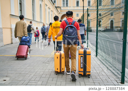 June 12, 2023 Saint Petersburg . Tourists walking with luggage toward city 128887384