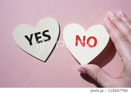 Yes or No symbol. Concept word Yes or No on wooden hearts. Businessman hand. Beautiful pink background. Business and Yes or No concept. Copy space 128887766