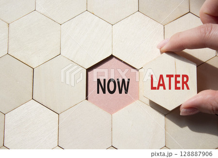 Now vs Later symbol. Concept word Now vs Later on wooden comb puzzle. Businessman hand. Beautiful pink background. Business and Now vs Later concept. Copy space 128887906