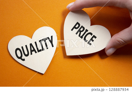 Price or Quality symbol. Concept word Price or Quality on wooden hearts. Businessman hand. Beautiful orange background. Business and Price or Quality concept. Copy space Price or Quality symbol. Concept word Price or Quality on wooden hearts. Businessman hand. Beautiful orange background. Business and Price or Quality concept. Copy space 128887934