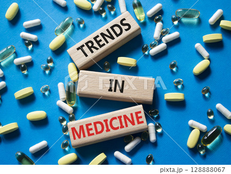 Medicine symbol. Concept words Trends in Medicine on wooden blocks. Beautiful blue background with pills. Medicine concept and Trends in Medicine. Copy space Medicine symbol. Concept words Trends in Medicine on wooden blocks. Beautiful blue background with pills. Medicine concept and Trends in Medicine. Copy space 128888067