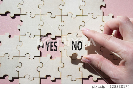 Yes or No symbol. Concept word Yes or No on wooden puzzle. Businessman hand. Beautiful pink background. Business and Yes or No concept. Copy space 128888174