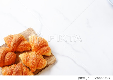 クロワッサン - 焼き立てのクロワッサンがサービングボードにのせられた朝の風景 128888505