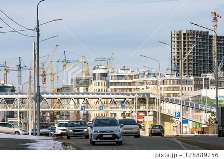 Cars drive on a road in a city under construction. 128889256