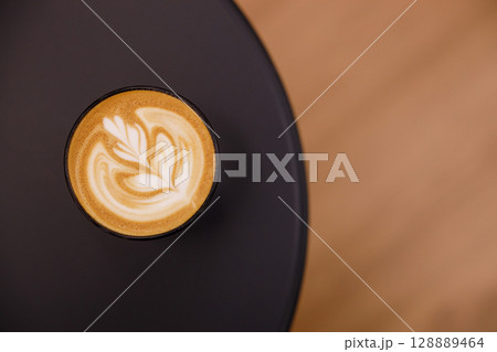 Cup of hot milk latte coffee on table. Cup of hot milk latte coffee on table. 128889464