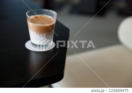 Glass of delicious cold milk chocolate on black wooden table background. 128889475