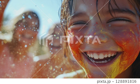 Closeup of a happy child with vibrant Holi powder celebrating with friends 128891816