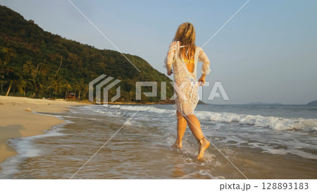 Woman in a White Tunic on the Beach, near the Sea. Blonde in Sun Woman in a White Tunic on the Beach, near the Sea. Blonde in Sun 128893183