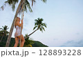 Sexual woman spends her vacation at the seaside. The girl is swinging on a swing. Sexual woman spends her vacation at the seaside. The girl is swinging on a swing. 128893228