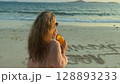 Woman walks on sunset on beach against background of sea. Girl i Woman walks on sunset on beach against background of sea. Girl i 128893233