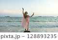 Woman stand on a reef rock stone in sea on sunset. Girl on beach Woman stand on a reef rock stone in sea on sunset. Girl on beach 128893235