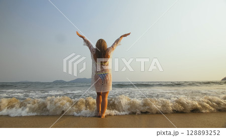 Woman is Wetting her Hair in a White Tunic on the Beach, near th Woman is Wetting her Hair in a White Tunic on the Beach, near th 128893252