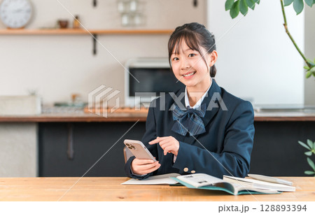家でスマホを使って勉強,宿題,リビング学習する中学生,高校生,小学生,生徒の女の子 128893394