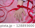 リボンを巻いた子どもの小さな手のアップ 128893600
