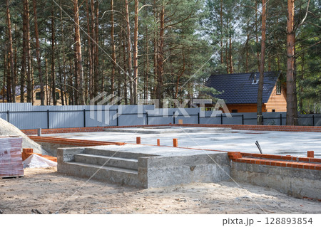 Concrete slab of foundation of house with laid pipes start of construction on project. Construction of cottages, design, engineering communications. 128893854