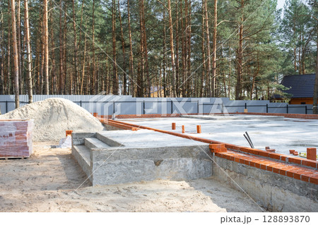 Concrete slab of foundation of house with laid pipes start of construction on project. Construction of cottages, design, engineering communications. 128893870