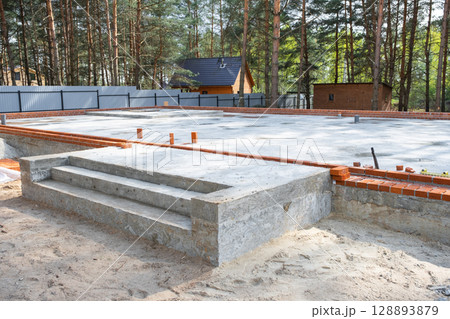 Concrete slab of foundation of house with laid pipes start of construction on project. Construction of cottages, design, engineering communications. 128893879