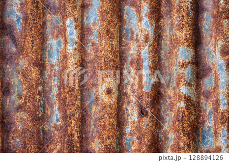 An old rusty metal sheet roof textured. Rust is an iron oxide formed by the reaction of iron and oxygen in the catalytic presence of water or air moisture. 128894126