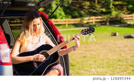 Hippie woman playing guitar in van car Hippie woman playing guitar in van car 128895344