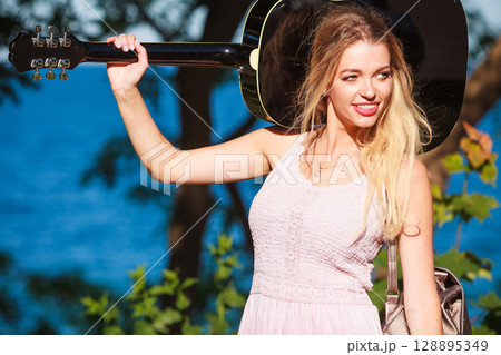 Blonde woman with acoustic guitar on seaside 128895349
