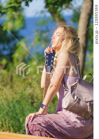 Woman playing acoustic guitar in park 128895369