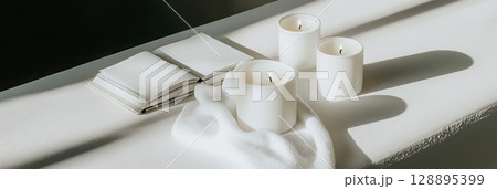 White candles on stacked books casting shadows, perfect for calming home decor background 128895399