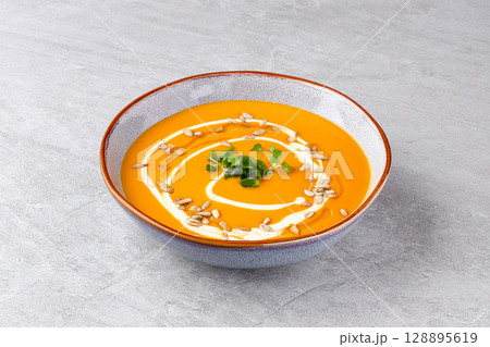 Silky Roasted Carrot Pumpkin Soup with Creamy Drizzle and Seeds 128895619