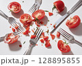 Sliced tomatoes and forks scattered on white surface, creating playful and chaotic scene 128895855