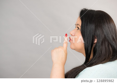 Woman asking for silence with finger on lips 128895982