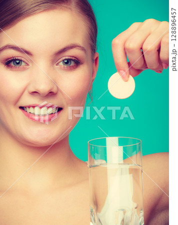 Woman holding glass with water and effervescent tablet Woman holding glass with water and effervescent tablet 128896457