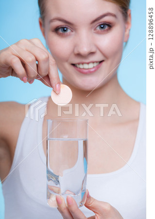 Woman holding glass with water and effervescent tablet 128896458