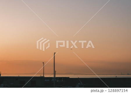 [タルイサザンビーチ]夕日の中を飛ぶ飛行機 128897154