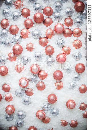 A white background with a lot of pink and silver balls. 128897311